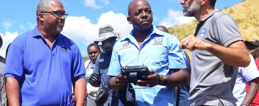 Minister of Agriculture and Fisheries, Hon. Pearnel Charles Jr. (centre), in discussion with Director of Agriculture and Fisheries at Food For the Poor, Nakhle Hado (right), while Chief Strategic Officer, Environmental Solutions Limited, Stephen Jones, looks on. They were in the process of observing a drone (foreground) being used to irrigate an onion farm in St. Thomas, during a tour on Thursday (February 16).